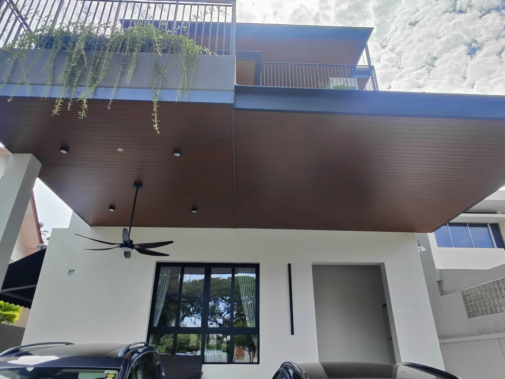 Roofing above a house entrance with a timber-look ceiling finish and a fan