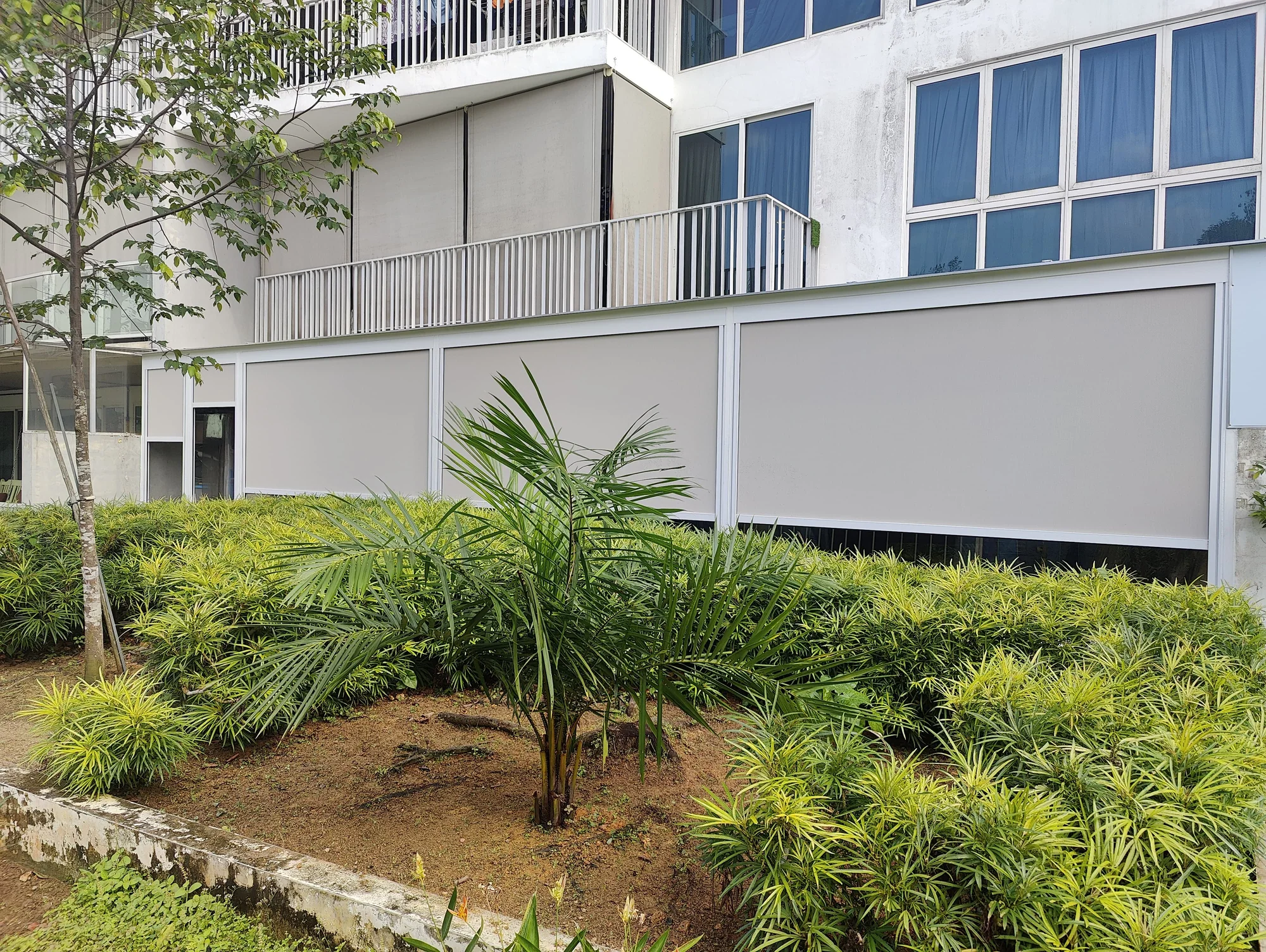Outdoor blinds across the side openings of a house beside a garden